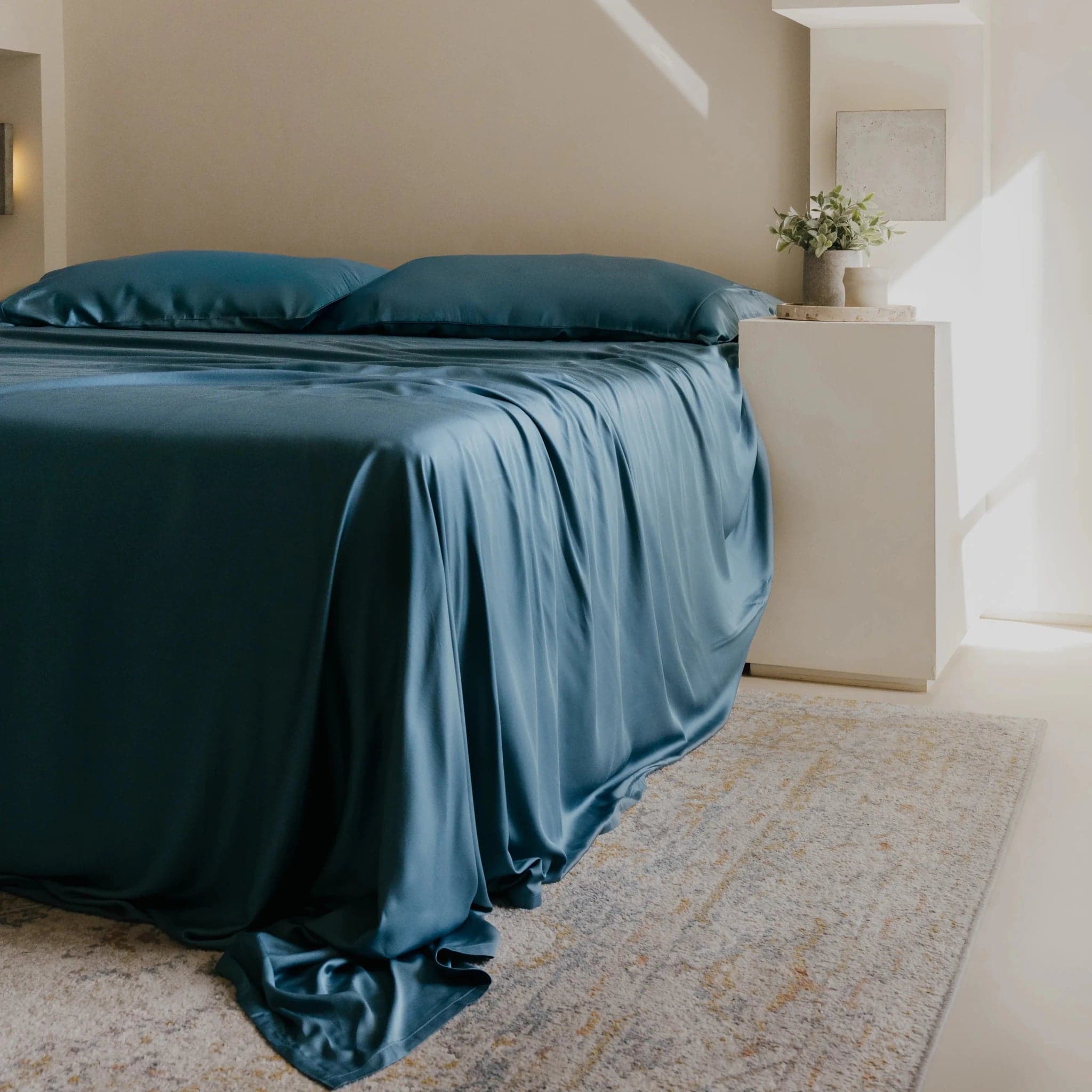 Gokotta ClassicBreeze sheet set in Storm, a deep teal blue, on a made bed with two matching pillowcases and the flat sheet draped to the floor