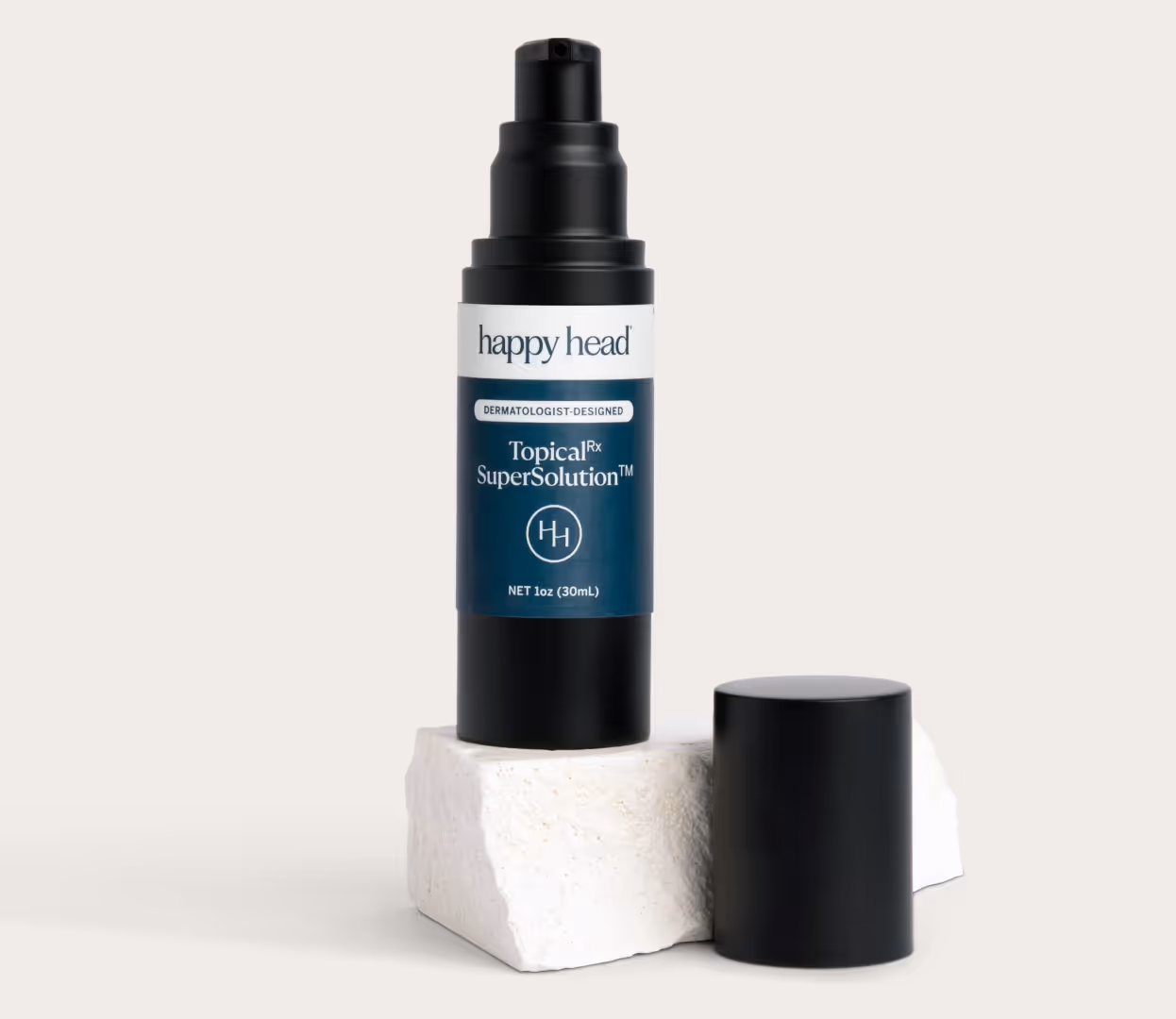 Black airless pump bottle of Happy Head Topical Rx SuperSolution, labeled Dermatologist-Designed and Net 1oz (30mL), standing on a white stone block with its black cap beside it against an off-white background