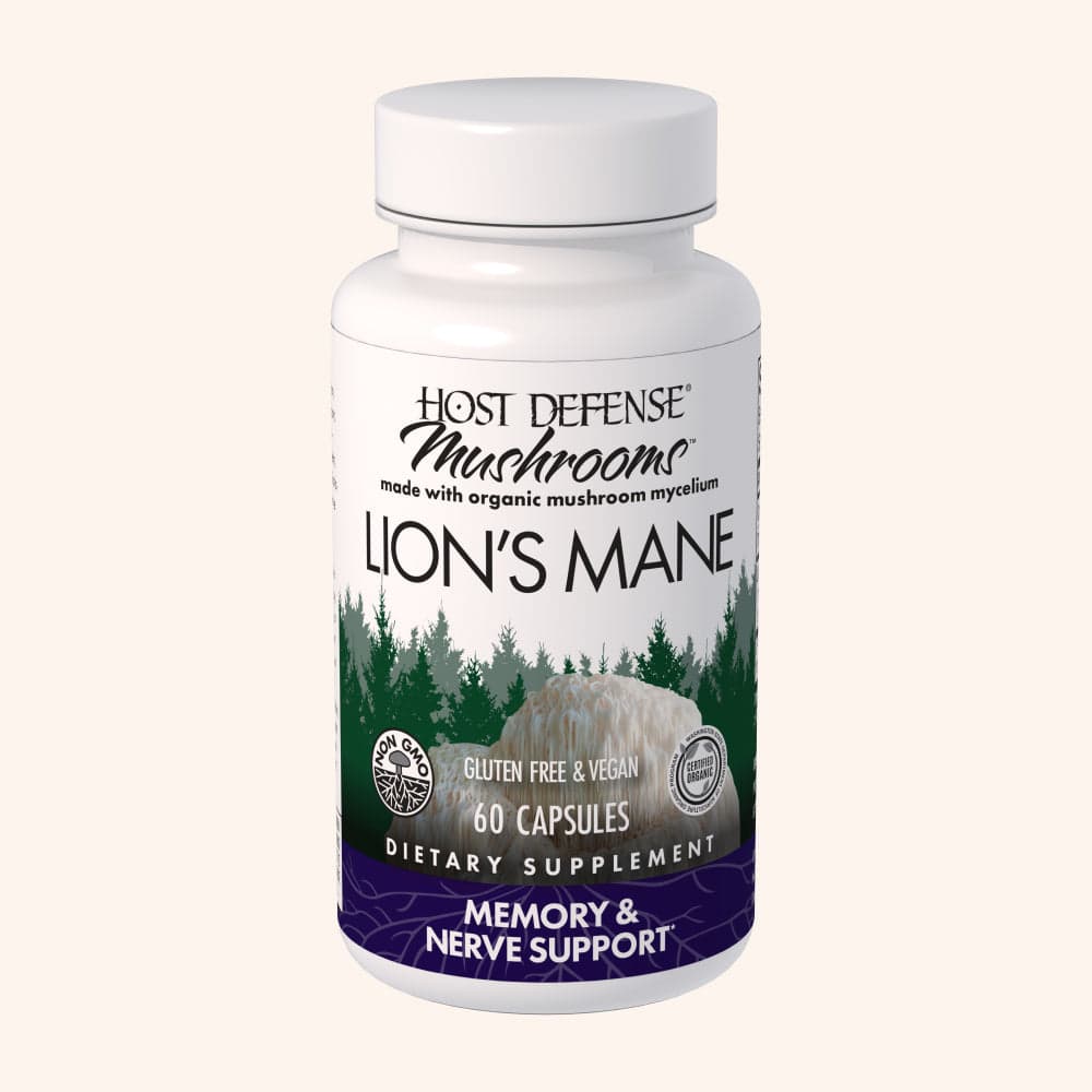 Host Defense Lion's Mane 60 capsule bottle with a white screw cap and a forest and mushroom label, standing upright on a plain cream background