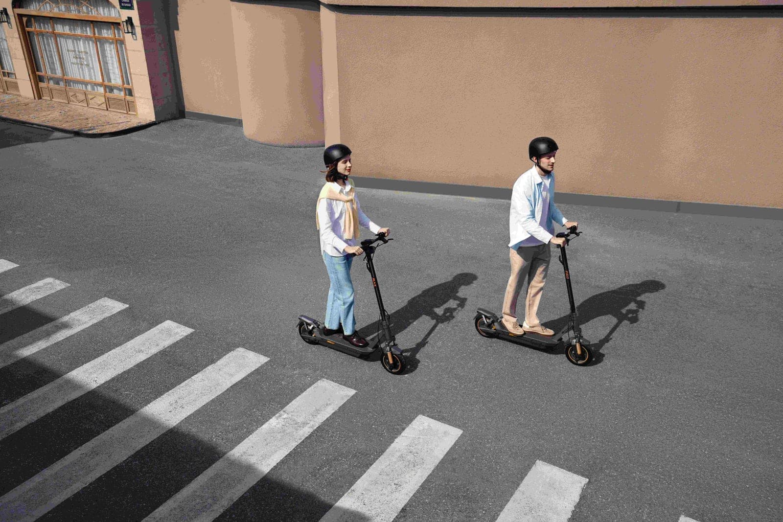 A Navee GT5 Max electric scooter ridden across a marked crosswalk beside a second Navee scooter of a different model, photographed from above