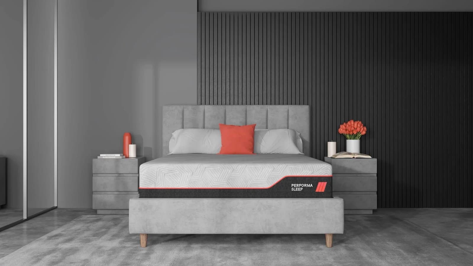 PerformaSleep Hybrid 12 inch mattress with a white quilted top and a black base panel with red piping, on a grey upholstered bed frame in a room render